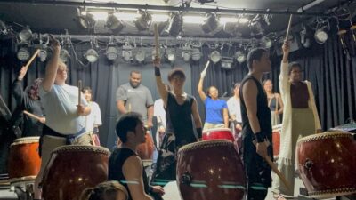 A group of people play traditional Japanese drums.