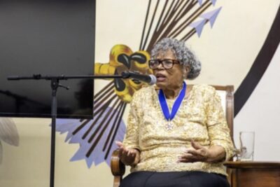 Dr. Opal Lee sits in front of a microphone and speaks.