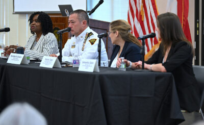 A group of four people sit behind microphones at a table.