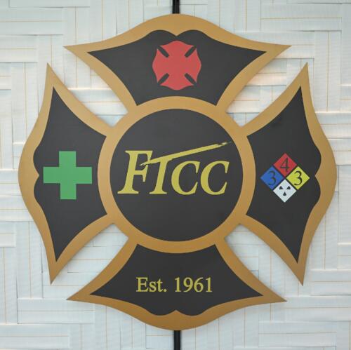 A close-up of a fire insignia with FTCC's logo in the center that hangs on the wall in the training center.