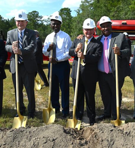 A close-up photo of Mike Causey, Charles Evans, Larry Keen and Glenn Adams wearing hard hats and holding shovels.